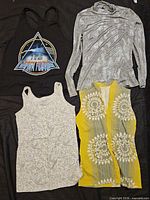Four garments laid flat: Pink Floyd tank, grey long-sleeve top, ivory tank, yellow patterned pants