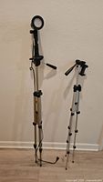 Both tripods standing fully extended against wall