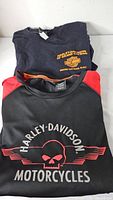 Two folded Harley-Davidson shirts showing chest graphics and colours