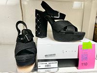 Pair of shoes on top of box displaying front, platforms, size label and box