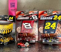 Front view of three packaged NASCAR diecast cars and loose hot rod