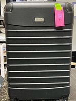 Front view of black Prestige hard shell suitcase showing ribbed shell, logo plate and wheels