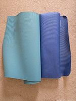 Two yoga mats side by side, partially unrolled to show colors and surface texture