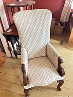 Front view of armchair showing upholstery, carved arms and front legs
