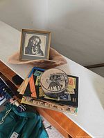 Overview showing framed print on wood bowl, decorative tin on book stack
