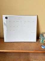 Front view of framed dry erase calendar board with magnet eraser