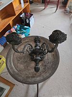 Front view of ornate two-arm metal candle sconce on tray table