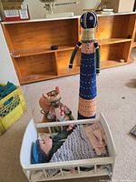 Group shot showing baby doll in cradle, beaded tall doll, small horn-headdress doll and partially visible fourth figure