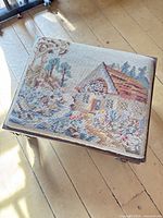 Top view of footstool showing entire needlepoint cottage scene