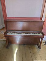 Front view of upright piano showing full keyboard and pedals