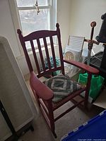 Front angled view of red wooden rocking chair with seat cushion