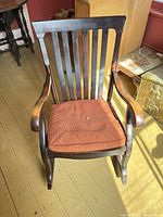 Front view of wooden slat-back rocking chair with cushion