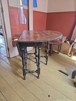Full view of table with one leaf down showing gateleg base and turned legs