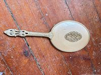 Back view of hand mirror showing cream enamel back and filigree medallion