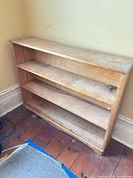 front view of solid wood bookcase showing three shelves and wear