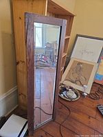 Full view of rectangular mirror with wood frame leaning against wall