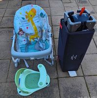 Rocker seat, folded playard in carry case, and bath seat on patio pavers