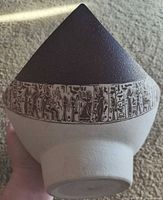 Side view showing full conical shape, dark brown upper glaze and Egyptian motif band