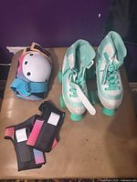 Pair quad roller skates with wrist guards and knee pads displayed on seat