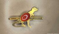 Front view showing dinosaur design and red cabochon