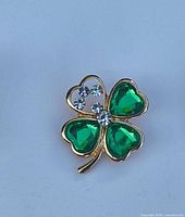 Gold-tone four-leaf clover brooch with green glass hearts and clear rhinestones
