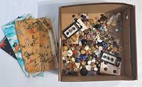 Box containing assorted buttons and adjacent fabric scraps