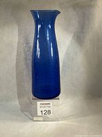 front view blue crackle glass carafe standing on clear riser