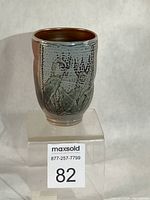 Full view of glazed handleless mug showing flower decoration and overall form