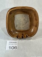 Front view of brown glazed square dish with central relief design