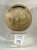 Front view of circular stoneware vase showing slot opening and relief leaf design