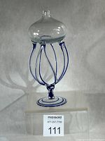 Full view of handblown glass oil lamp on acrylic riser