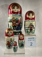 Frontal view of all five dolls showing painted village scenes