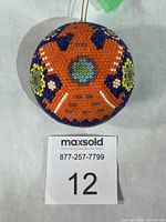 Front view of round beaded ornament showing eagle motif and scale card