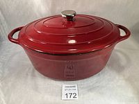 Full view of Dutch oven with lid showing oval shape, side handles, stainless knob, exterior condition