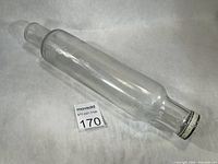 Full view of clear glass rolling pin lying flat