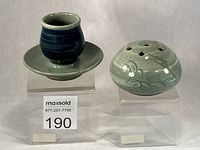 Both celadon pieces side by side on stands
