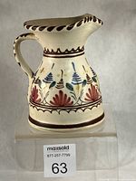 Front view showing spout, handle and floral decoration