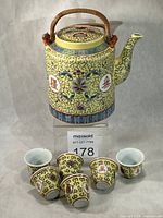 Front view of teapot with six cups