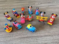 Group shot of twelve small Disney character vehicle toys on wooden surface