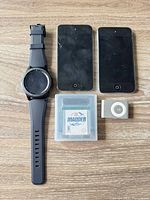 Group shot of all five items: Samsung Gear S3 watch, two iPod Touch units, iPod Shuffle, Madden game cartridge