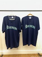 Front view of both navy Seattle Mariners jerseys with wordmark