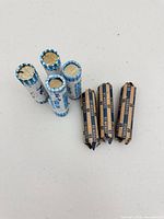 Group of nine nickel rolls: five blue-white standing, four brown-blue lying flat