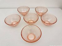 Six pink glass bowls arranged to show size and swirl design