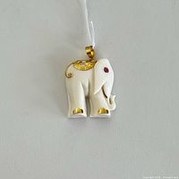Front view of carved bone elephant pendant with gold accents and ruby eye