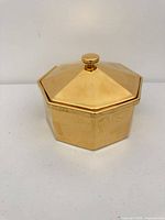 Closed container showing gold exterior and knobbed lid