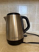 Side view of Black+Decker stainless steel electric kettle with power cord