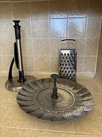 All three items—steamer basket expanded, paper towel holder, box grater—on kitchen counter