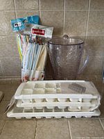 Group view of pitcher, two ice cube trays and sealed pack of straws