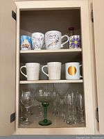 Cabinet with mugs on two shelves and assorted glassware below