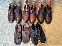 Six pairs of men’s shoes arranged on carpet showing overall condition and types